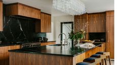 kitchen island with dark wood cabinets and dark soapstone worktops and backsplash intricate contemporary clear glass ceiling light above the island