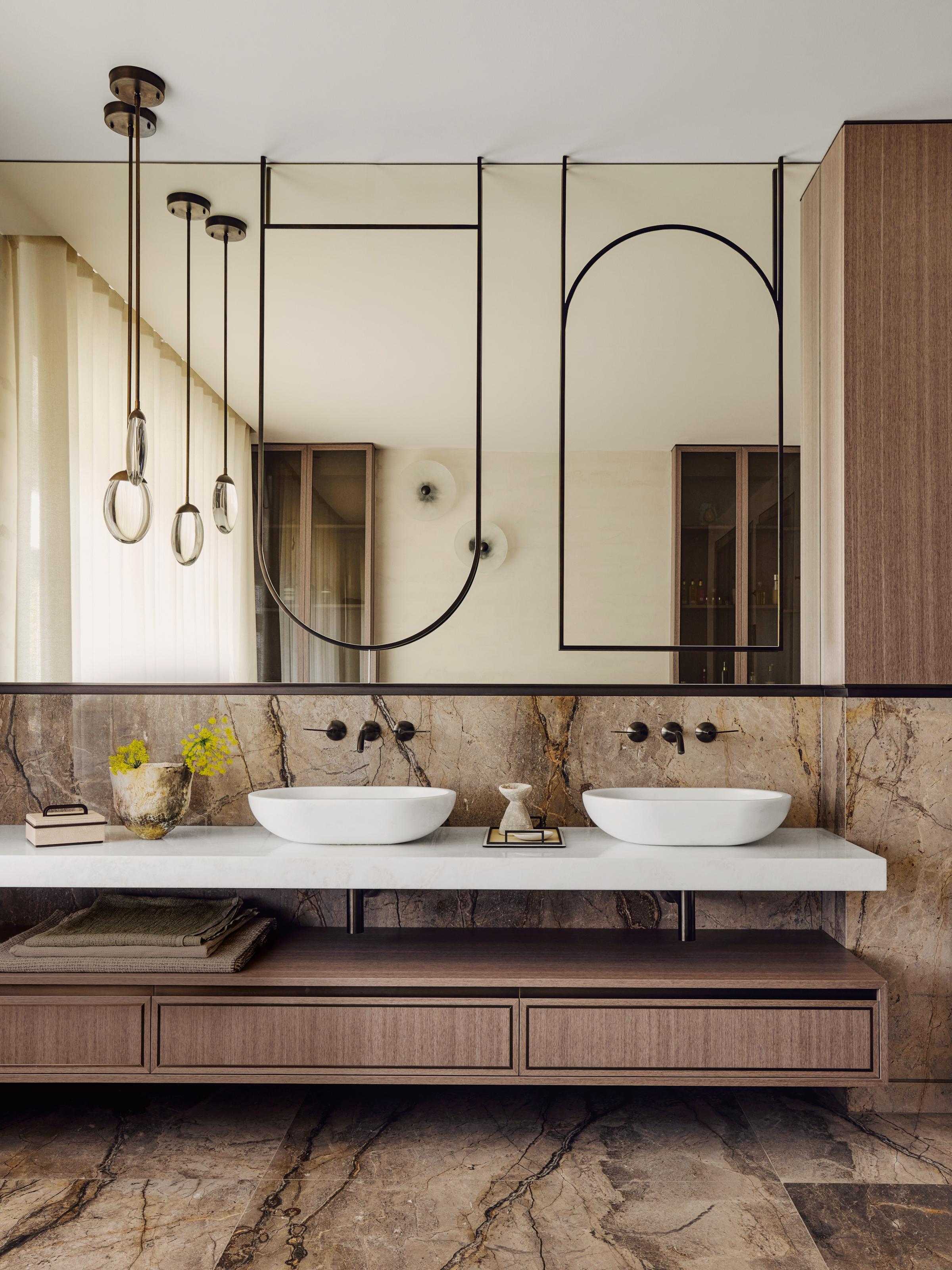 Bathroom with full-width mirror, wood and stone vanity, brown stone floor and backsplash