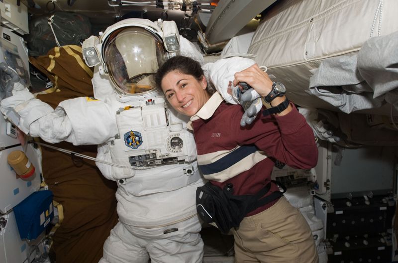 Astronaut Nicole Stott, STS-128 mission specialist, poses for a photo with a NASA spacesuit on the middeck of the space shuttle Discovery on Aug. 30, 2009 during docking activities at the International Space Station.