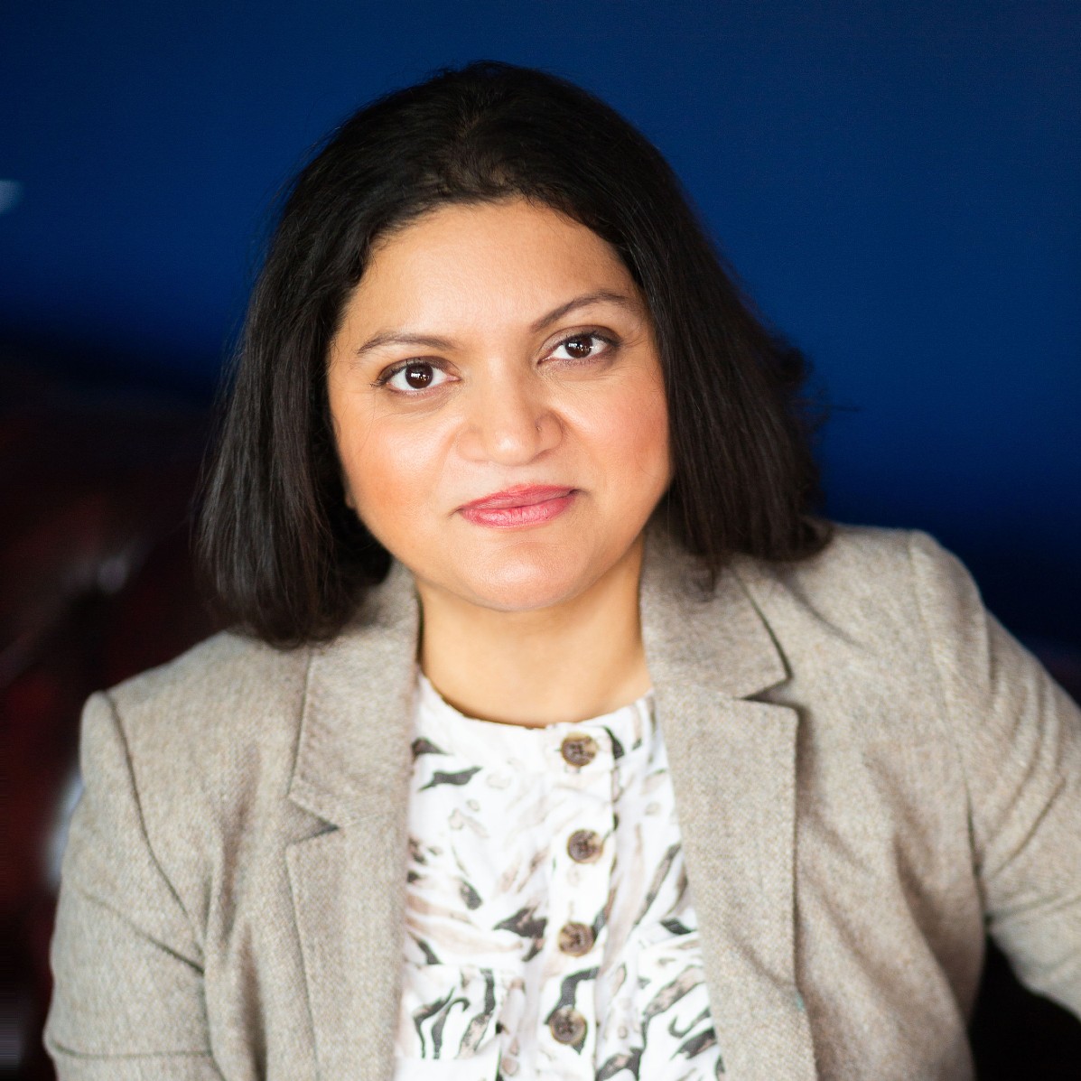 Woman with short black hair wearing grey blazer