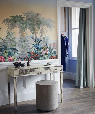 Bedroom with jungle motif wallpaper, dressing table and rounded pouffe seat, door leading to walk in closet, curtain separating the spaces