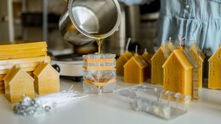 A person pours liquid wax into a candle mould