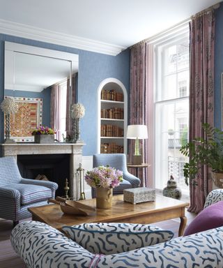 Formal living room ideas with blue walls, arched built-in bookcase, pink curtains and blue and white seating