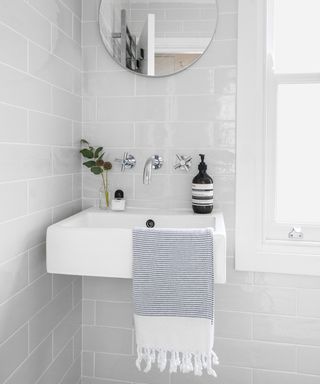 A wall-mounted basin against grey metro tiles