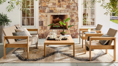 a cozy patio sitting area with two chairs, a loveseat, a coffee table, and a large fireplace