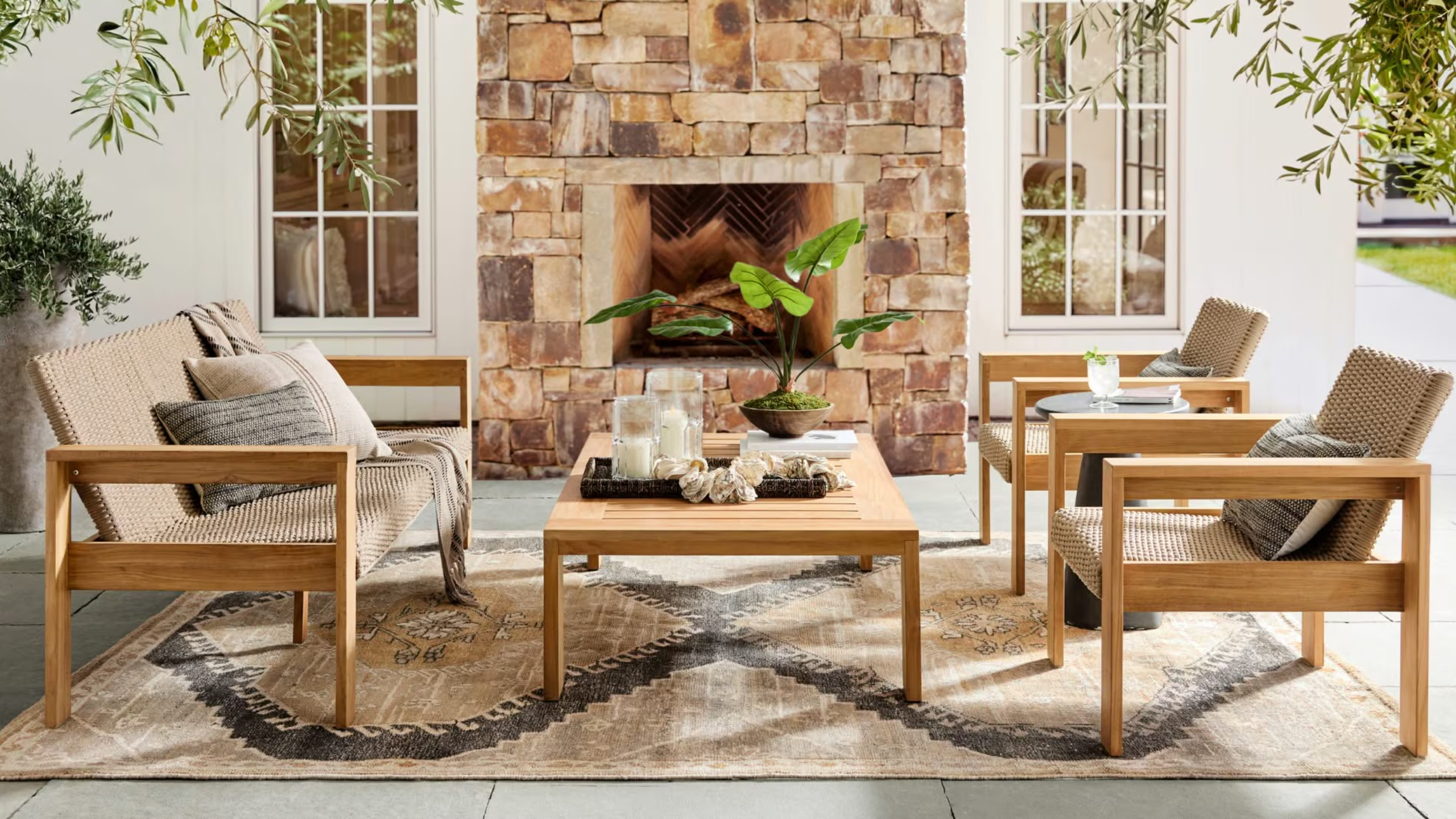 a cozy patio sitting area with two chairs, a loveseat, a coffee table, and a large fireplace