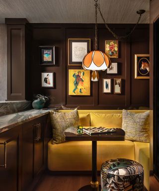 A bright yellow sofa in a moody room with a gallery wall and hanging light fixture