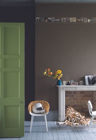 Painted floorboards in green room with wooden painted door, brick fireplace and small accent chair