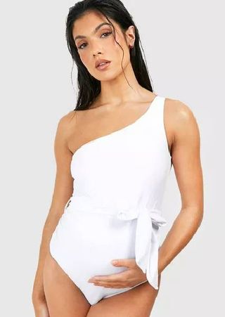 A pregnant model wearing a white, maternity tie string swimsuit from Boohoo.