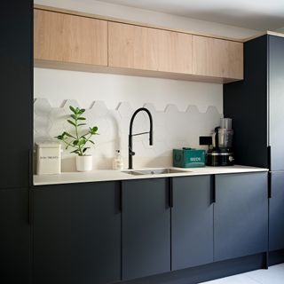 Black kitchen with slab doors and light oak upper cabinets