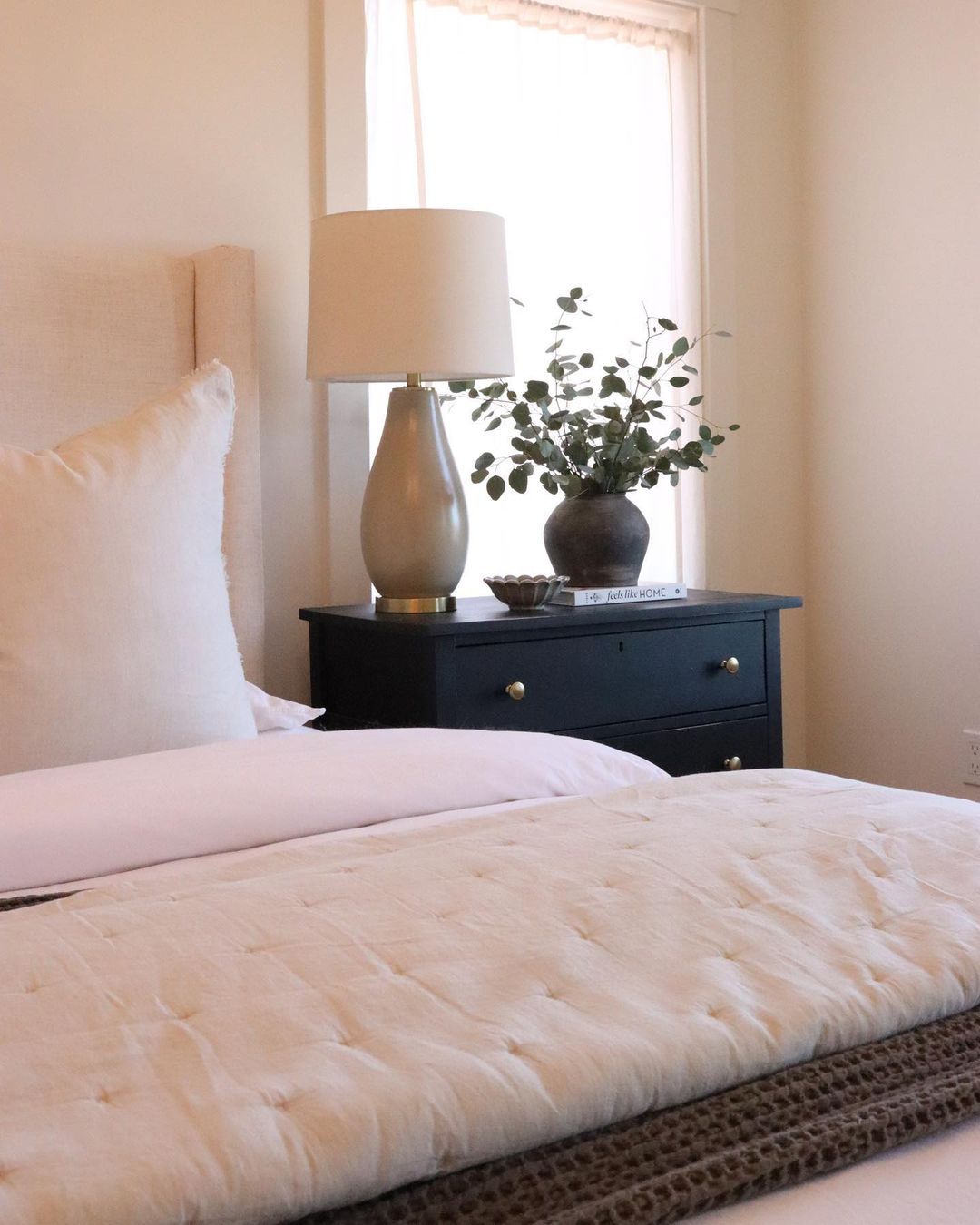 Kamar tidur merah muda dengan meja samping tempat tidur biru tua dengan dekorasi di atasnya