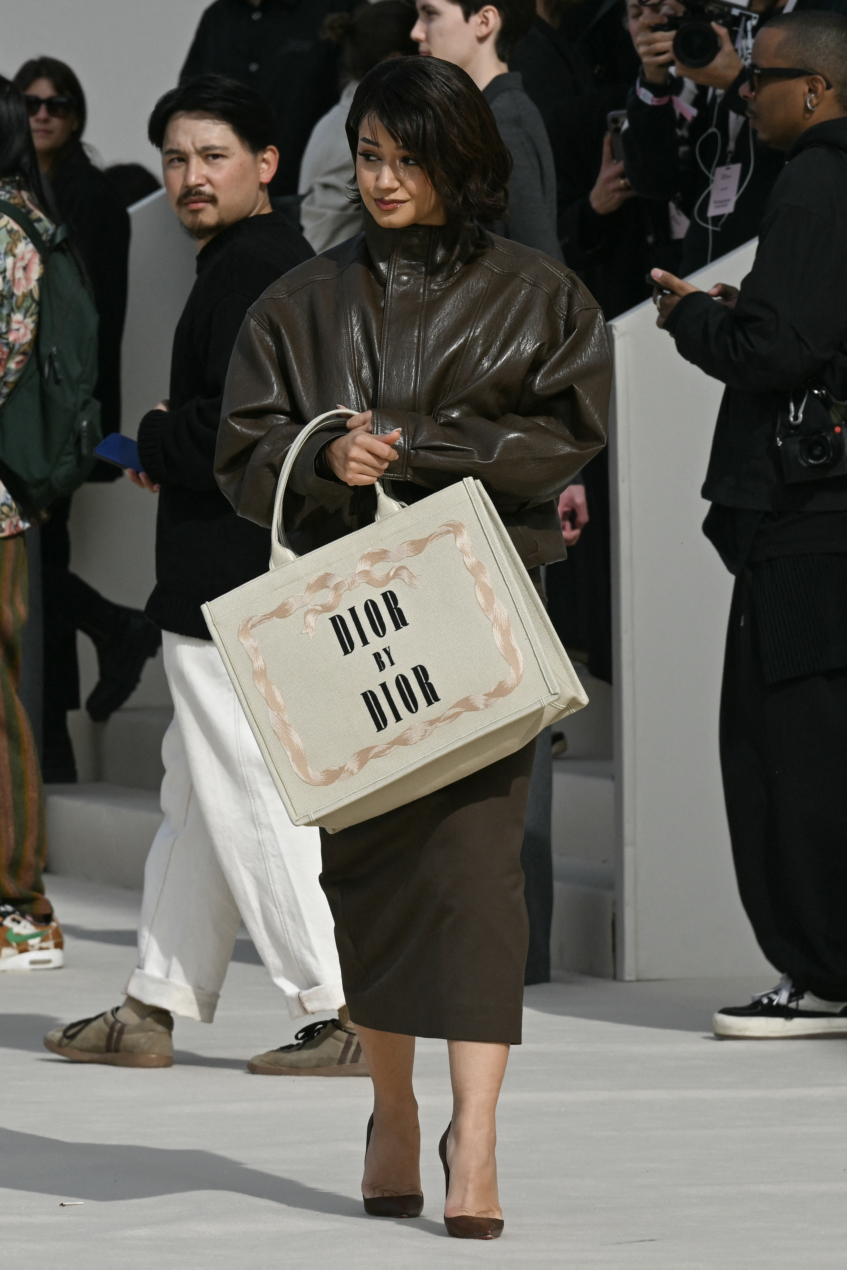 a guest at Dior&#039;s Paris Fashion Week show carrying a Dior book tote