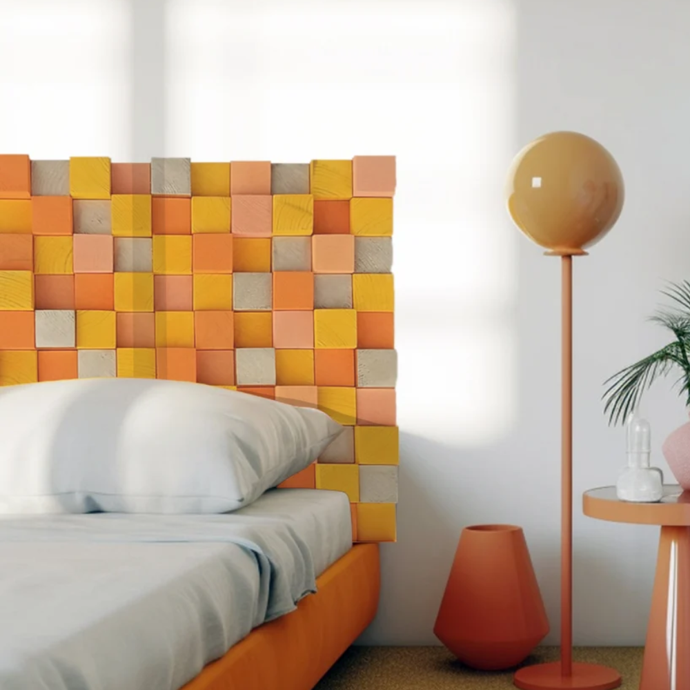 Orange wooden headboard with lots of colourful squares, next to orange lamp and vase
