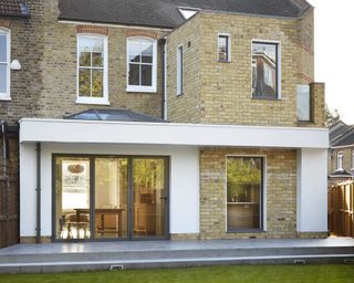 Two storey rear extension in brick and white render with bifold door