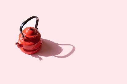 a red tea kettle on pink background