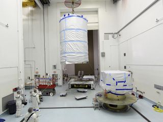 On Aug. 12, 2011, a crane lifts the protective canister that will enclose NASA's twin Gravity Recovery and Interior Laboratory spacecraft, at right, during transport to the launch pad. The lunar probes are attached to a spacecraft adapter ring in their si