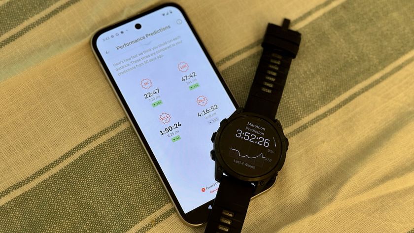The Strava app showing Performance Prediction times for the author&#039;s current condition for 5K, 10K, half marathon, and full marathon races, with a Garmin Fenix 8 draped above the bottom-right of the phone showing a different marathon prediction time.
