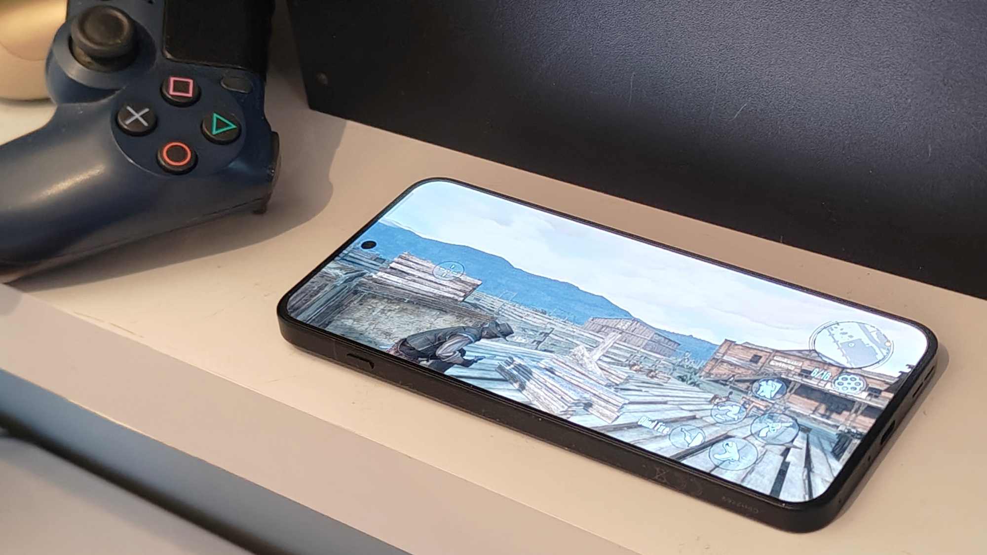 Red Dead Redemption playing on an Android phone, with a PS4 and controllers in the background.