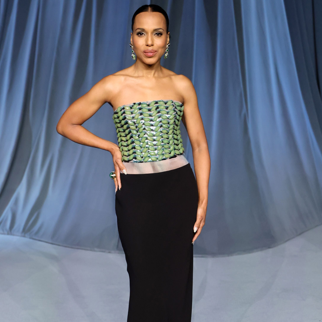 Kerry Washington wearing a slicked bun hairstyle and strapless gown. She has her hand on her hip and is smiling at the camera. 