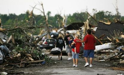 People walk through a demolished neighborhood the day after a deadly tornado ripped through Joplin, Missouri, leaving a path of destruction nearly one mile wide.