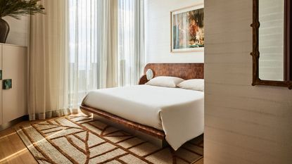 bedroom with burl wood headboard, storage, patterned rug, artwork above bed, and sheer curtains