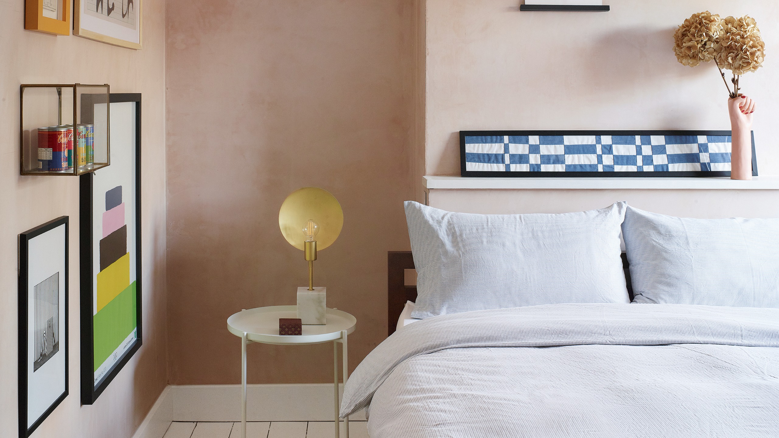 A 'peige' or plaster pink bedroom with lots of framed art on the wall