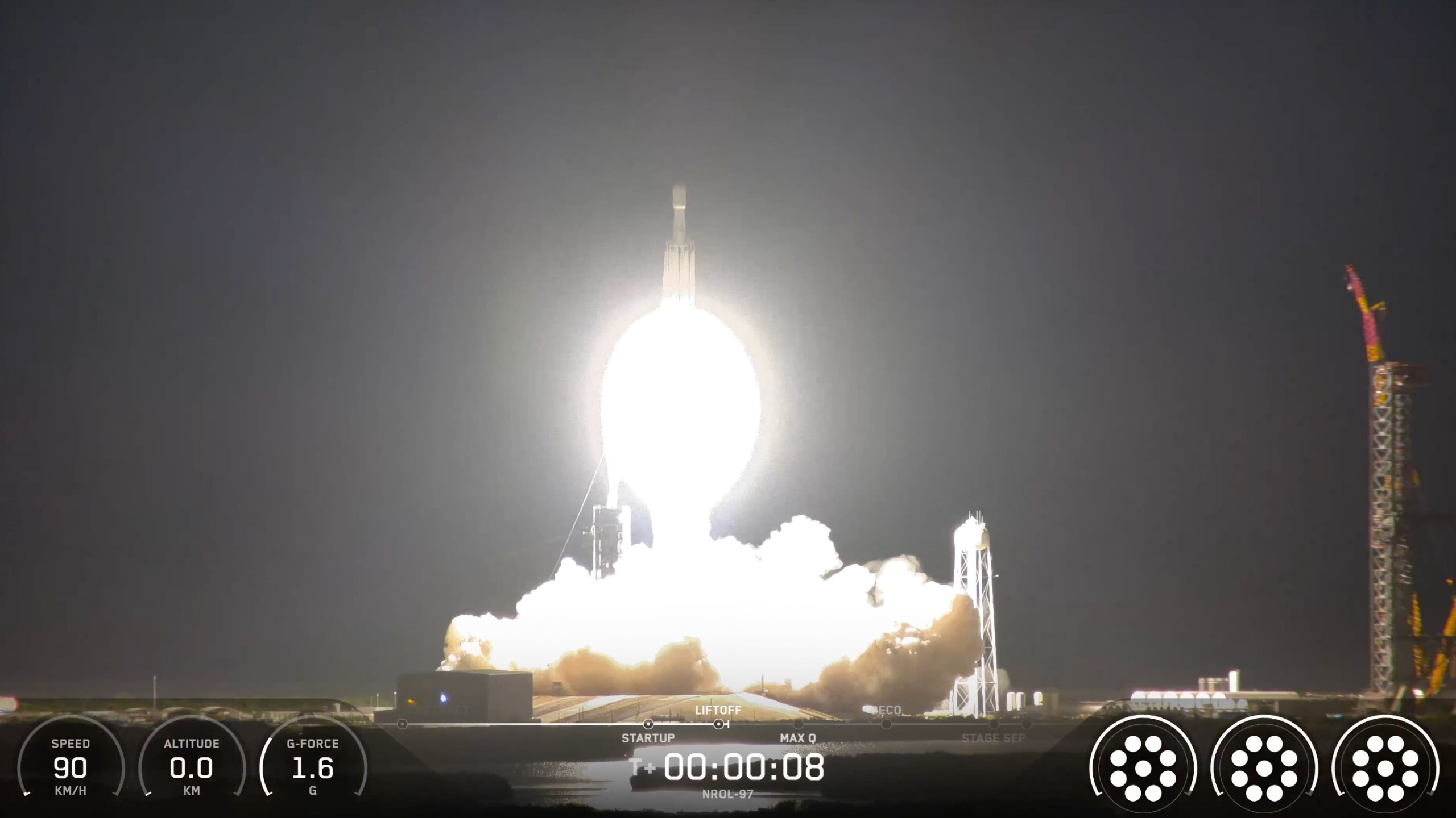 a big white rocket launches into a dark night sky