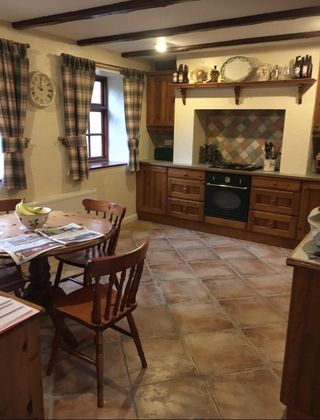 Before pic of kitchen with dark wood units, wooden dining table and chairs, and tiled floor
