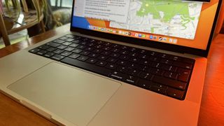 A 2023 14-inch MacBook Pro on a wooden counter, near a retro lamp.