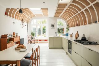 a lght green kitchen with a curved rafter roof overhead looking out to patio doors