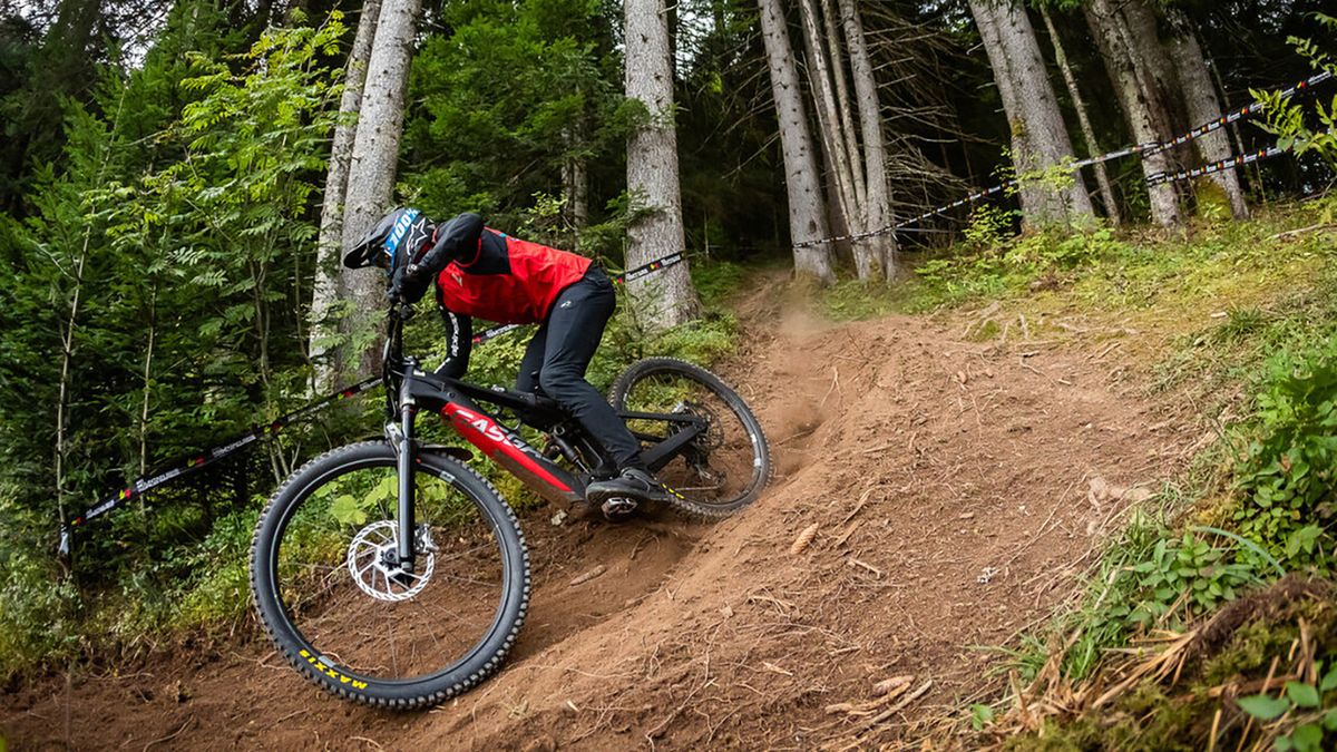 Rider on e-MTB on downhill track through woods