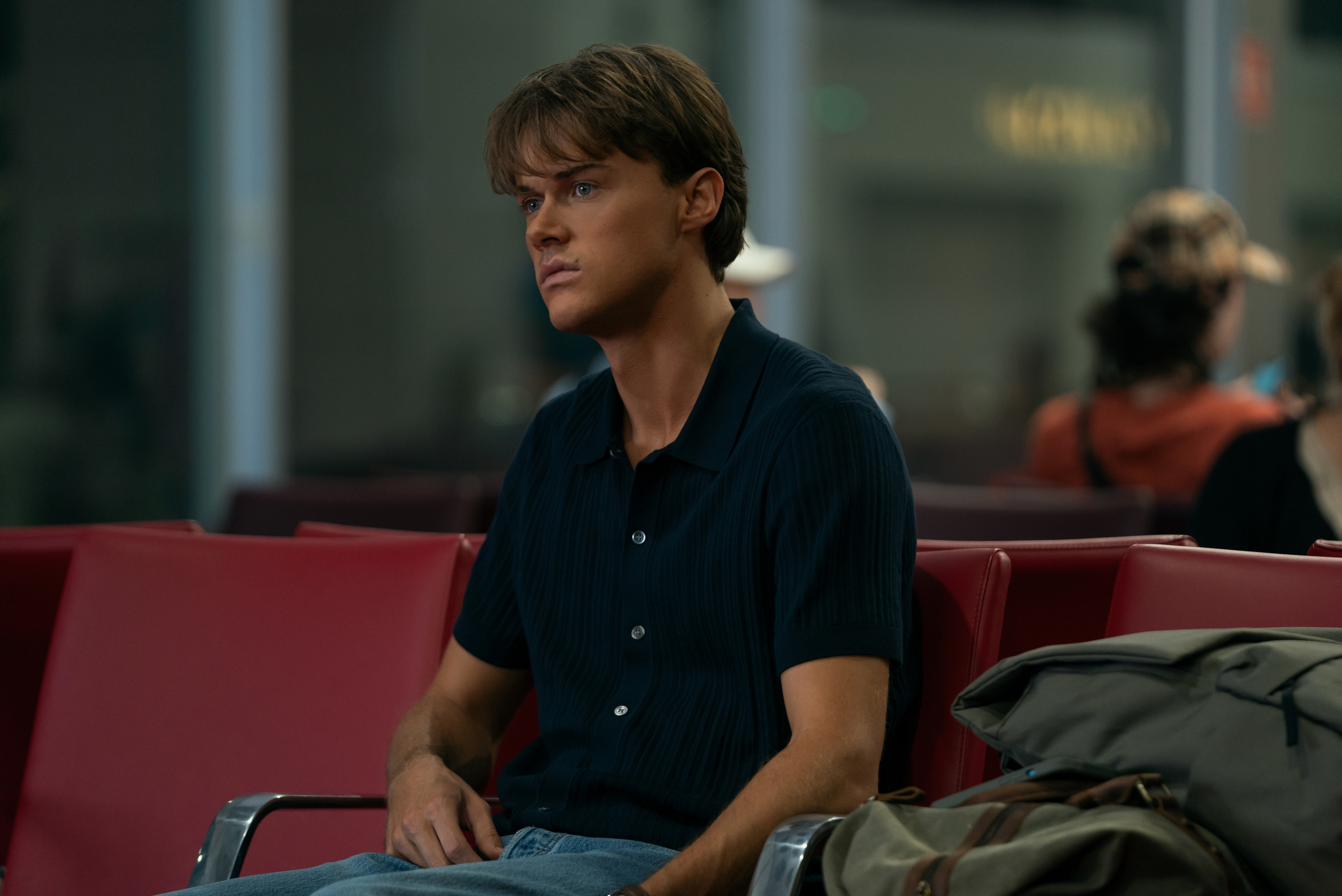 christopher briney as conrad sitting at the airport in a still from the summer i turned pretty season 3