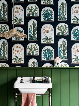 a bathroom with green wainscot panels and a cactus print wallpaper