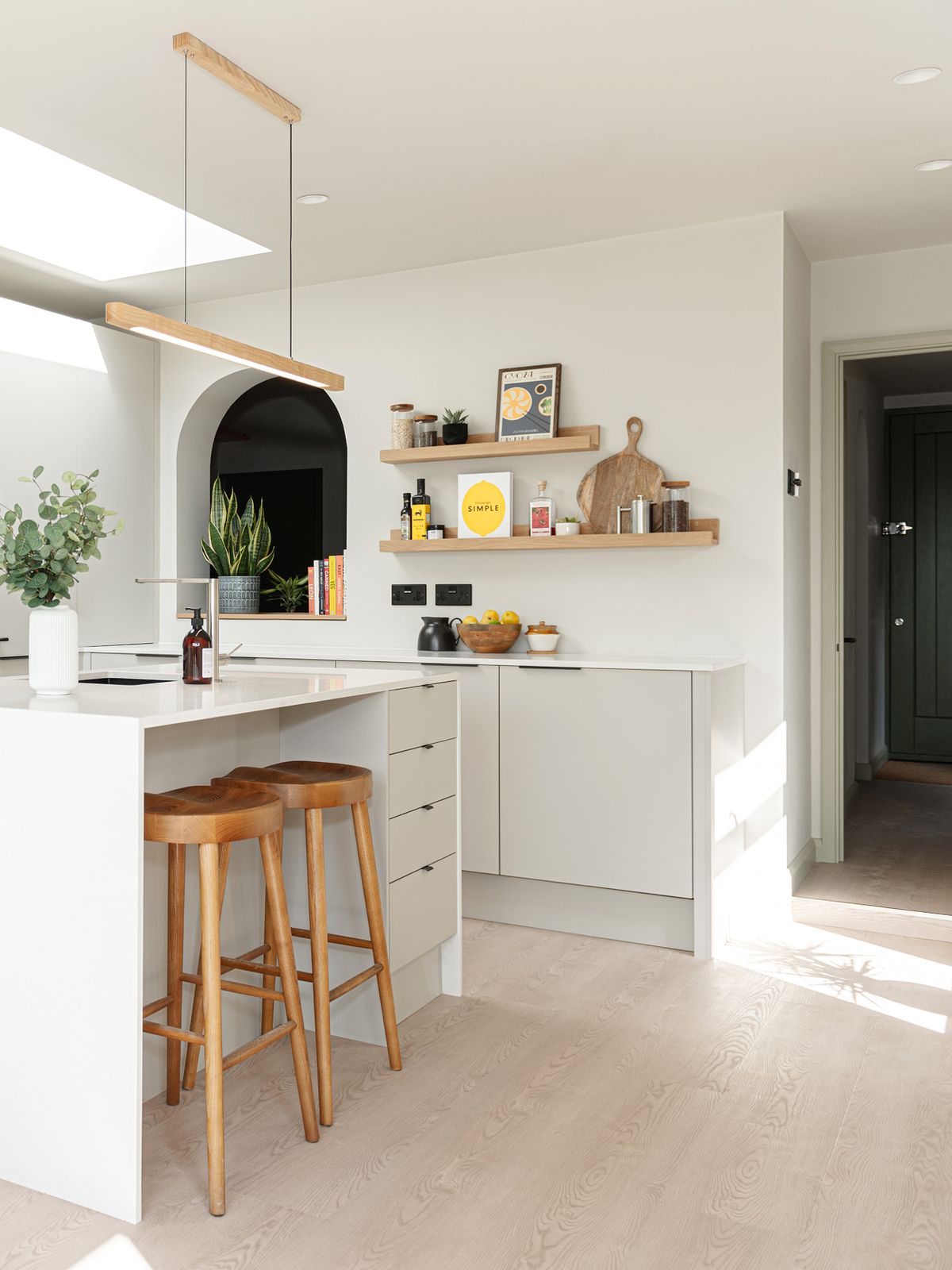 A bright white kitchen with an island with wooden stools