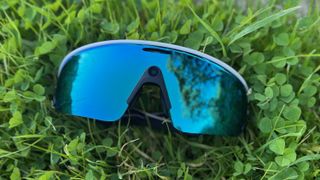 The Oakley Meta Vanguard smart glasses laying on grass.