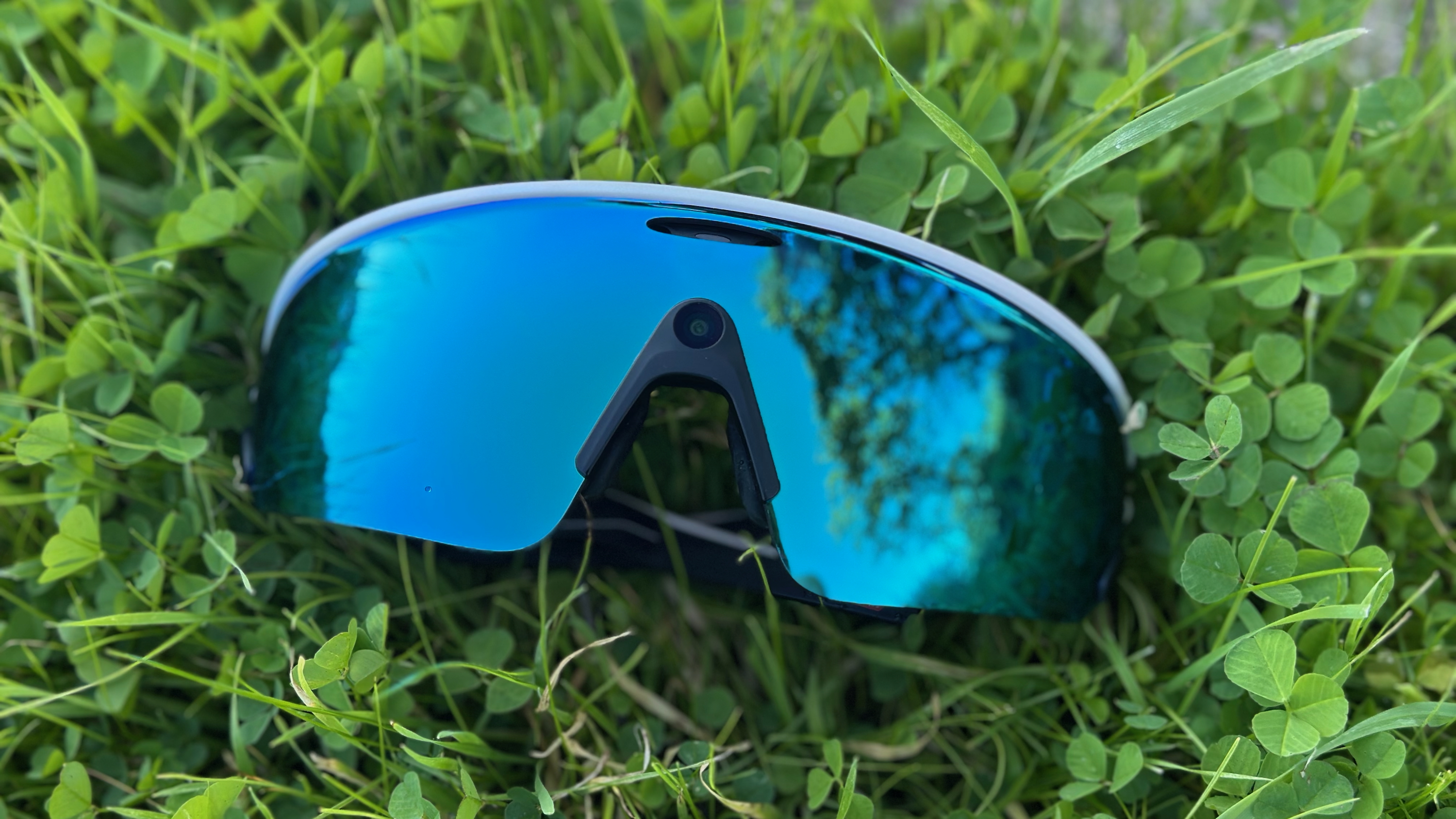 The Oakley Meta Vanguard smart glasses laying on grass.