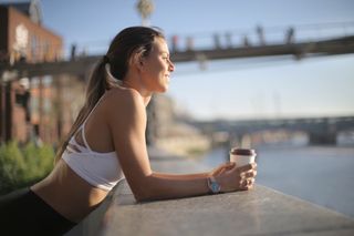 Sportive girl resting drinking a coffee and looking at the view