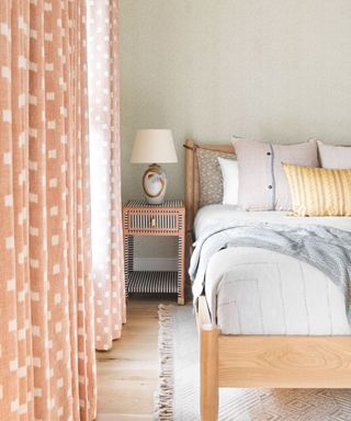 Peach drapes in a bedroom looking to striped bedside table