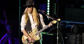 Jerry Cantrell wears a hat and dark sunglasses as he plays live with Alice In Chains. he is playing his trusty "Blue Dress" G&L S-style.