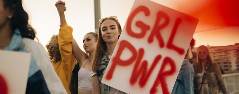 Portrait of women protesting with friends for human rights in city against sky