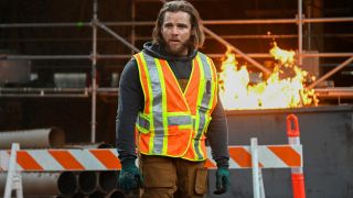 Max Thieriot as Bode standing in front of a fire wearing a construction vest in the Season 2 finale of Fire Country.