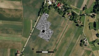 A four-sided underground structure that turned out to be an early medieval fortress caused crop marks in the field in satellite photographs. The barrows and tombs of the Neolithic cemetery were found to the north and south of the fortress during excavations of the site.