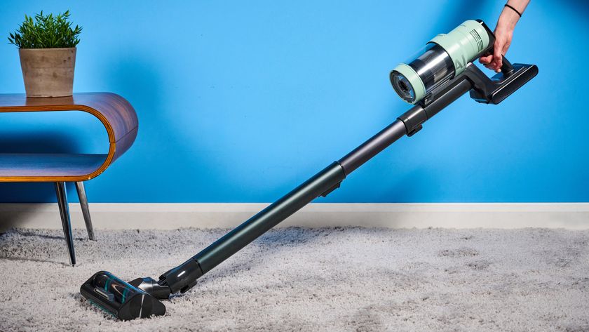 the samsung bespoke jet AI vacuum cleaner in mint green against a blue background, showing its ability to clean carpets and baseboards, as both a stick and a handheld