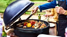 person cooking meant and vegetables on a large egg-style BBQ