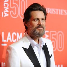 Jim Carrey with a thick beard wearing a white tux jacket.