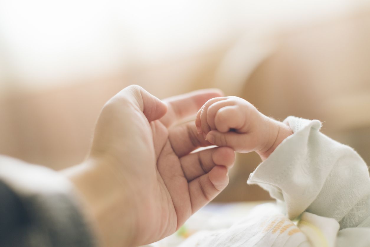 A woman holds a baby&amp;#039;s hand.