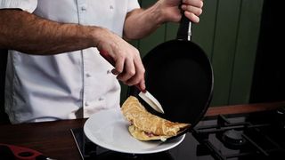 Hands rolling omelette up and on to plate