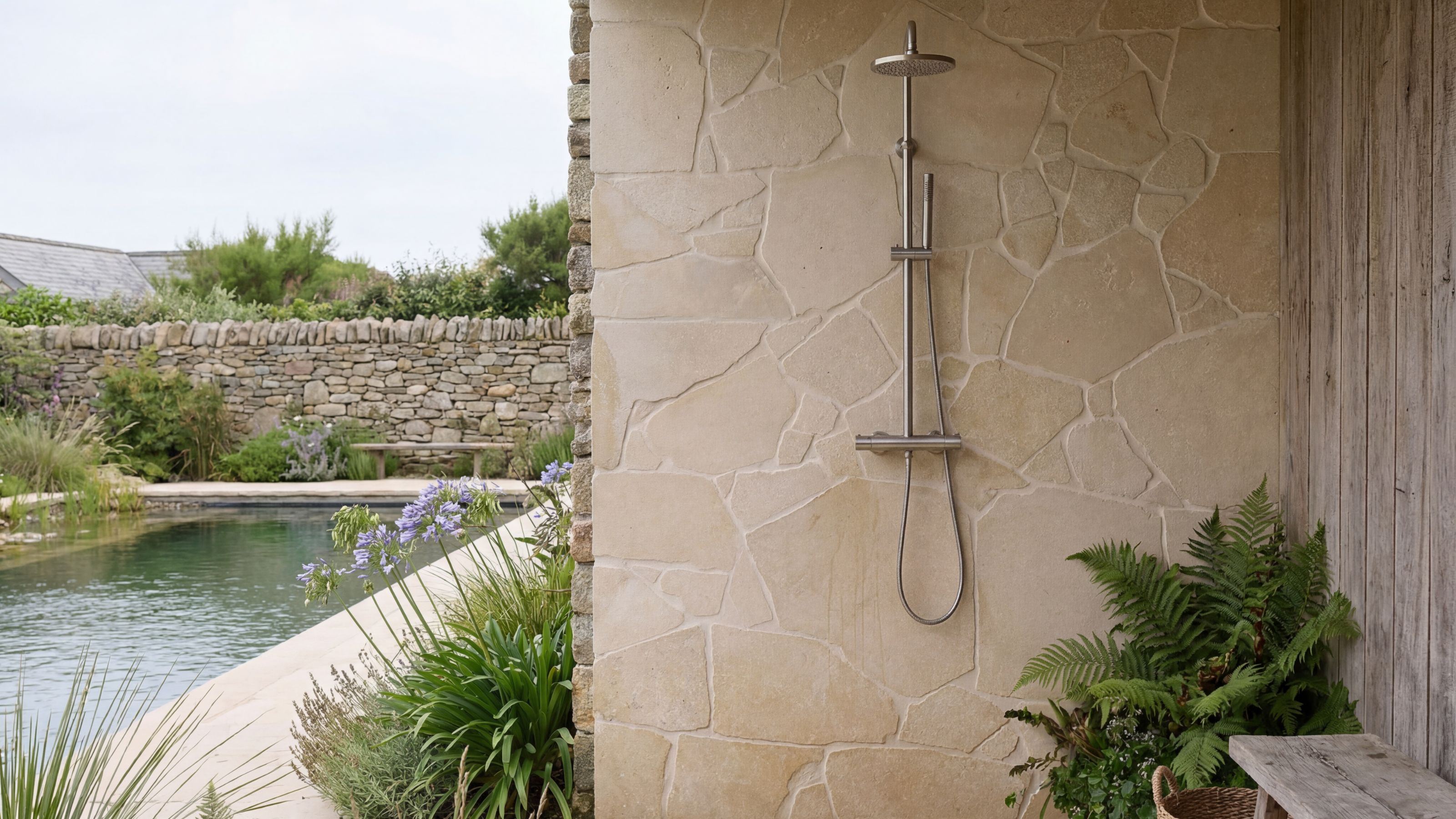 Outdoor shower with rustic tile screen and pool in background