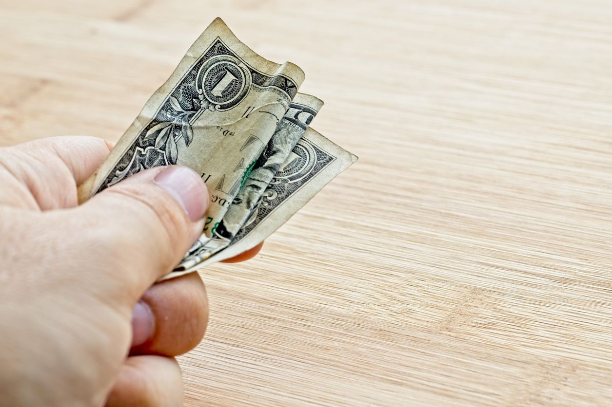 A man holds a dollar bill.