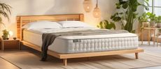 Our Simba Earth Escape mattress review image shows this luxury organic mattress on a wooden bed frame surrounded by green house plants